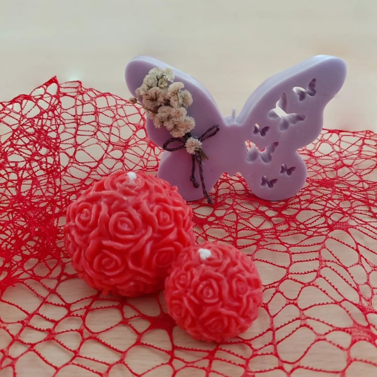 Bolas de cera cubiertas de rosas, en rojo, sobre una malla roja