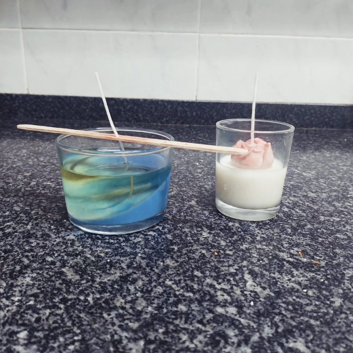 Cera azul en un vaso junto a una vela con rosa