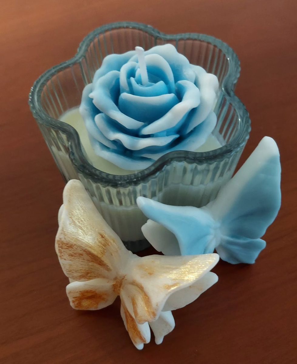 Rosa de cera azul en vaso con mariposas