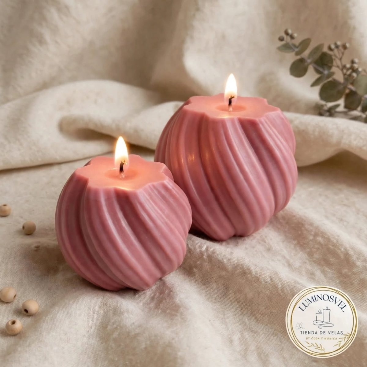 Dos velas rosas de cera con forma de torre, encendidas